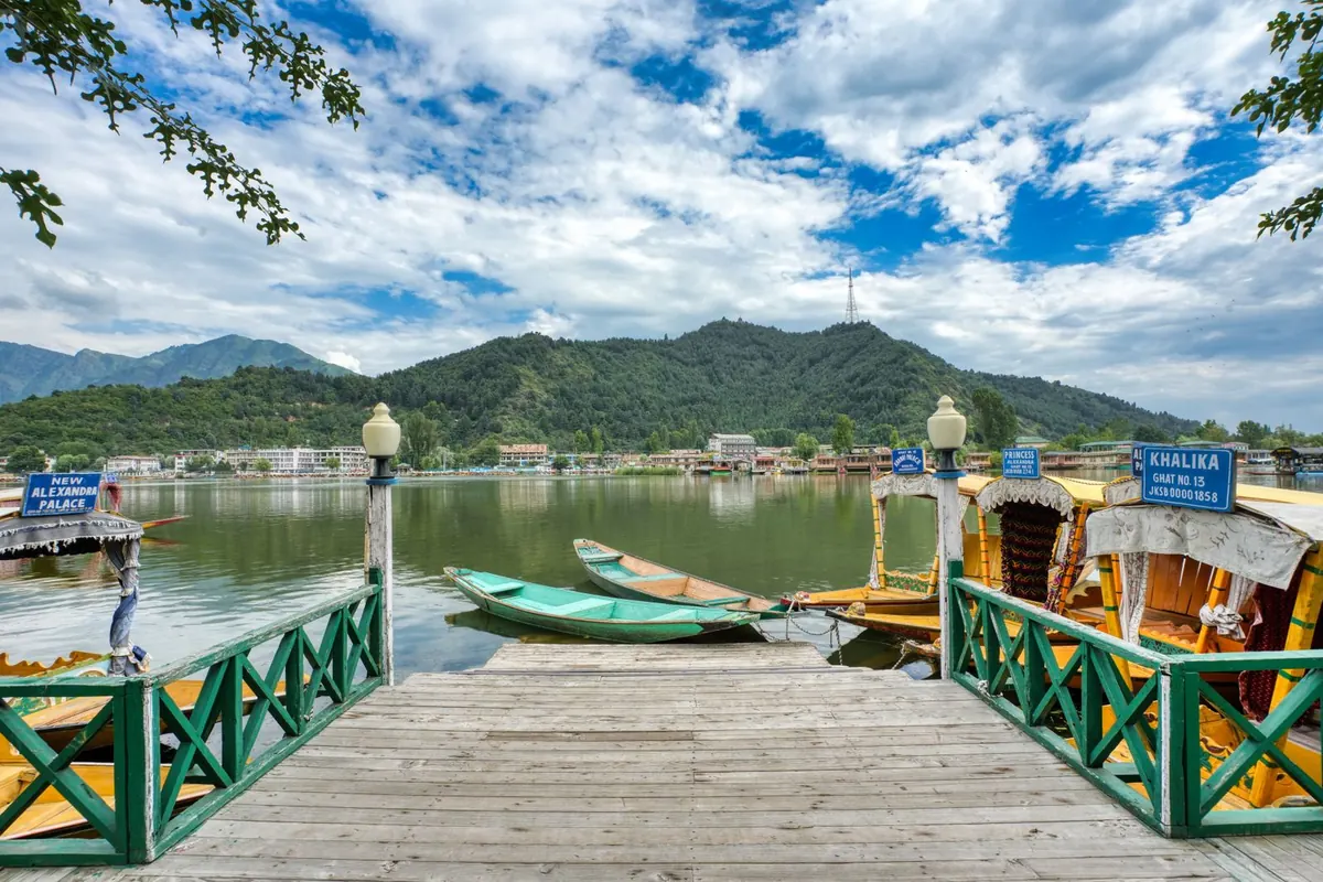 Visitors and shikaras at a Dal Lake jetty in Srinagar on a clear day, a typical scene on Kashmir's main tourist circuit