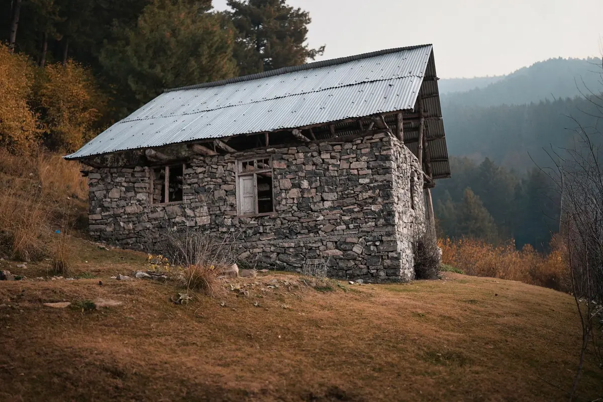 Stone cottage on a golden autumn hillside in the Kashmir mountains, typical October weather and colour