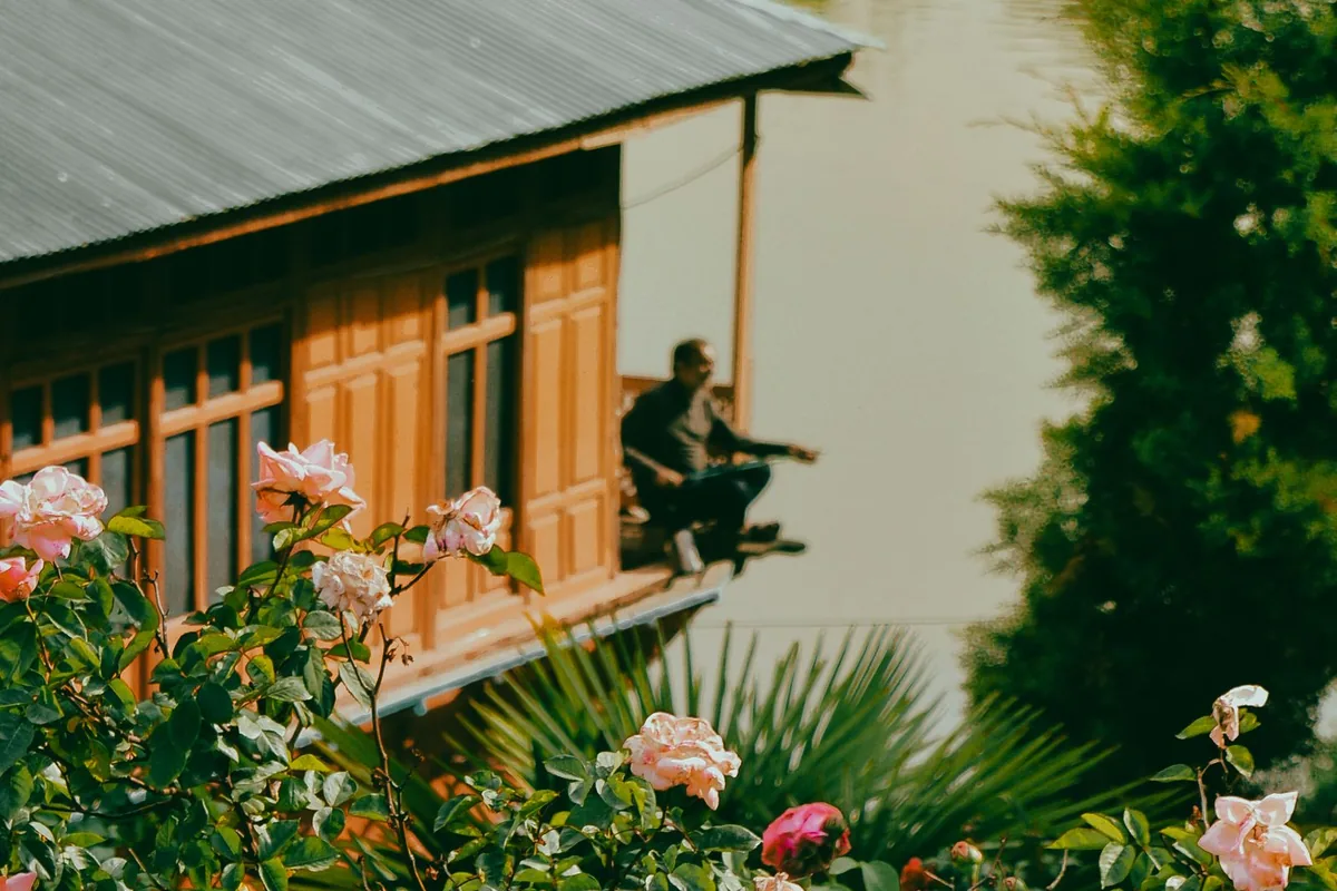 Carved wooden houseboat with a rose garden on the lake in Srinagar, a peaceful stay option for solo travellers in Kashmir
